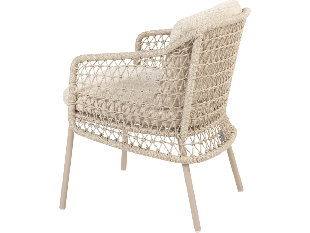 Puccini tuinstoel van 4 Seasons Outdoor schuin van achteren, met licht open vlechtwerk en beige kussens.
