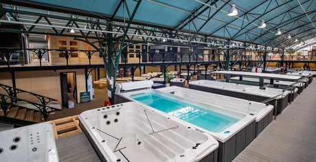Rijen spa’s en zwemspa’s in een overdekte showroom.
