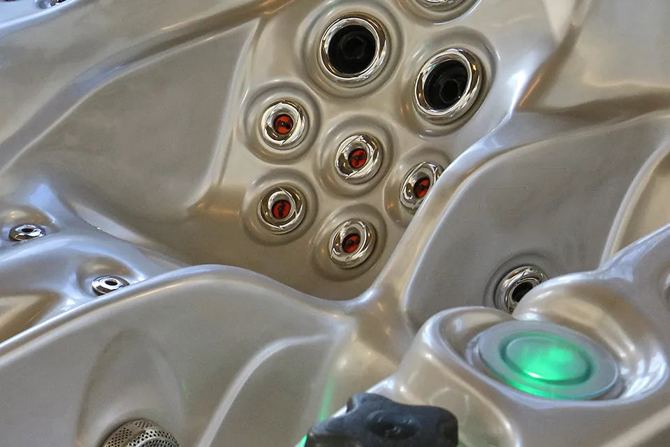 Close-up van massagejets in de rugleuning van een spabad en een groen verlichte bekerhouder.