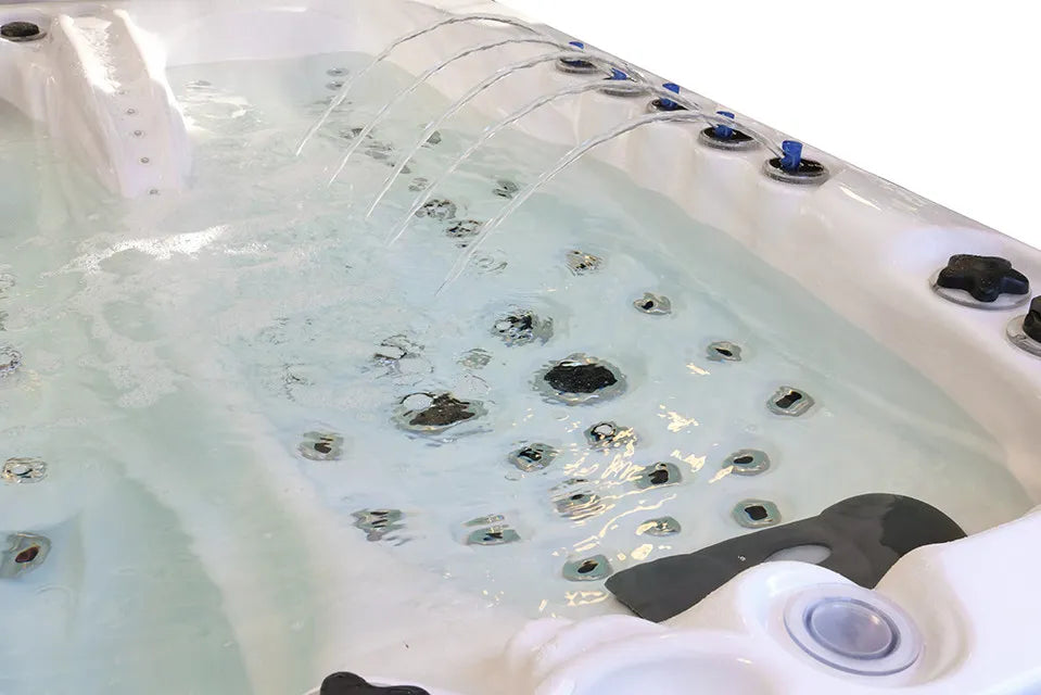Ligplaats met massagejets in een wit spabad, naast verlichte waterstralen langs de rand.