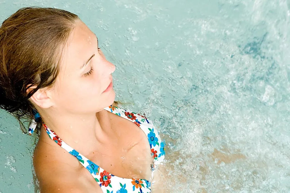 Vrouw in een spabad met bruisend water, van bovenaf gezien.