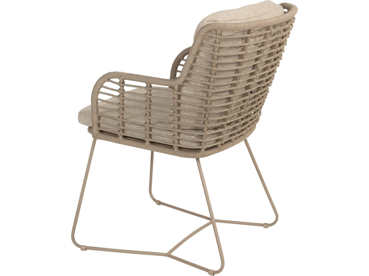 Fabrice tuinstoel van 4 Seasons Outdoor in Latte, schuin van achteren, met gevlochten rug, beige kussens en sledepoten.