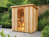 Fonteyn Retreat 180 buitensauna met een persoon op de bank achter de glazen deur, op een terras in de tuin.